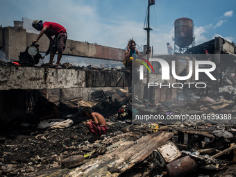 Residents collect fire debris to be sold in junk shops after a fire  broke out in a slum area in Tondo, Manila in the Philippines on April 1...