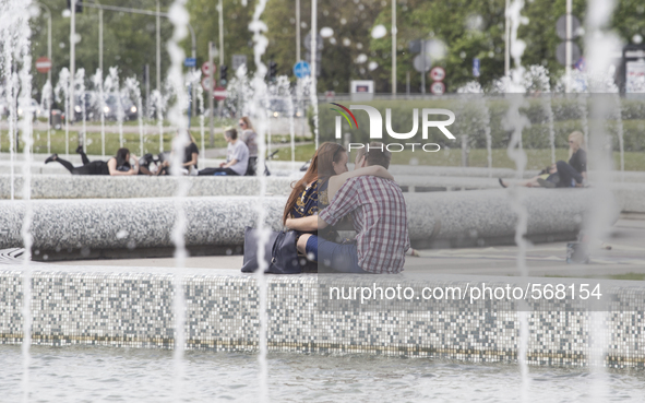 People relaxing in a fountains park on a warm spring day in Warsaw on May 5, 2015.
