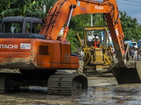 Heavy equipment operators tried to get rid of mud that filled the road due to flash floods in Poi Village, South Dolo Subdistrict, Sigi Rege...