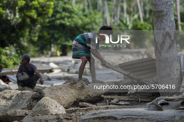 A child collects wood from his house that was lost in a flash flood in Poi Village, South Dolo Subdistrict, Sigi Regency, Central Sulawesi P...