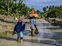 Residents crossed the road that was buried by mud due to flash floods in Poi Village, South Dolo Subdistrict, Sigi Regency, Central Sulawesi...