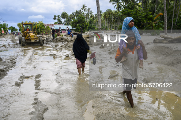 Residents crossed the road that was buried by mud due to flash floods in Poi Village, South Dolo Subdistrict, Sigi Regency, Central Sulawesi...