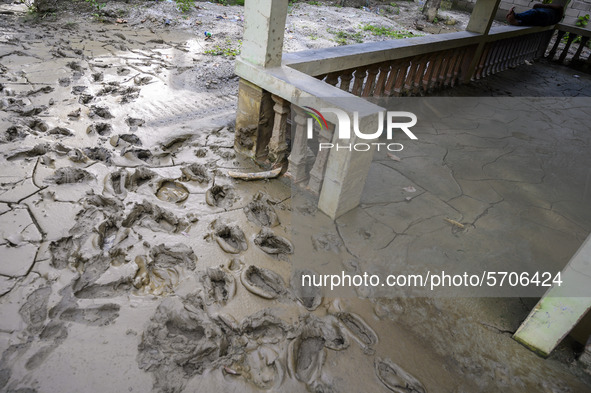 A resident sleeps on the porch of his house which was damaged and buried by mud due to being hit by flash floods in Poi Village, South Dolo...
