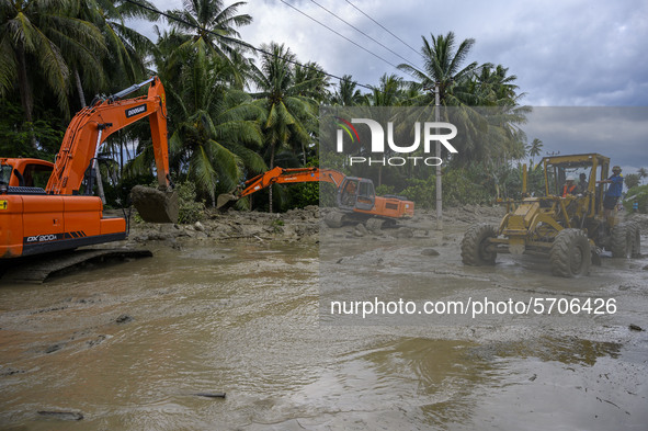 Heavy equipment operators tried to get rid of mud that filled the road due to flash floods in Poi Village, South Dolo Subdistrict, Sigi Rege...