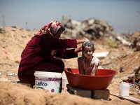 A Palestinian woman washed her son next to her home, which destroyed that witnesses said was destroyed during the 50-day war last summer, in...
