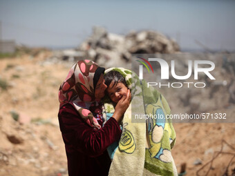  A Palestinian woman covers her son after washing with water next to family home, which destroyed that witnesses said was destroyed during t...