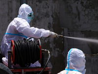 Health workers wearing Personal Protective Equipment (PPE) disinfect as a preventive measure against the spread of the new coronavirus COVID...