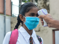 A school official checks the temperature of a student after their school after 115 days, the school that was shut down during the COVID-19 l...