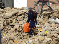 A rescue worker carrying a gas cylinder among the ruins of a collapsed building, where three persons have been confirmed died and nine injur...