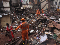 Rescue workers work at the site after portion of a building collapsed in Mumbai, India on July 17, 2020. Six people were killed and 15 rescu...