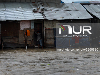 A man holds onto a stair railing as he walks in flooded street after the  river overflows due to incessant rainfall at a slum along the bank...