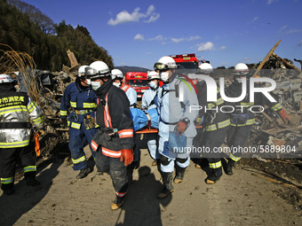 March 18, 2011-Rikuzen Takata, Japan-Rescue Team carry exhumed body on debris and mud covered at Tsunami hit Destroyed city in Rikuzentakata...