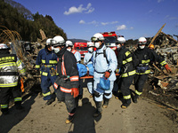March 18, 2011-Rikuzen Takata, Japan-Rescue Team carry exhumed body on debris and mud covered at Tsunami hit Destroyed city in Rikuzentakata...