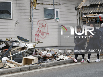 March 21, 2011-Ofunato, Japan-Shcoolgirl go to shcool on debris and mud covered at Tsunami hit Destroyed Industrial Area in Ofunato on March...