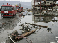 March 21, 2011-Ofunato, Japan-Rescue team searching burial body on debris and mud covered at Tsunami hit Destroyed Industrial Area in Ofunat...