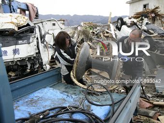 March 21, 2011-Ofunato, Japan-Native Survivors collect scrap iron on debris and mud covered at Tsunami hit Destroyed Industrial Area in Ofun...