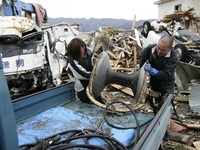 March 21, 2011-Ofunato, Japan-Native Survivors collect scrap iron on debris and mud covered at Tsunami hit Destroyed Industrial Area in Ofun...