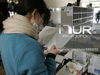 March 23, 2011-Rikuzen Takata, Japan-Volunteer women read surviver news of daily news paper at refugee camp in Rikuzentakata on March 23, 20...
