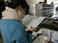 March 23, 2011-Rikuzen Takata, Japan-Volunteer women read surviver news of daily news paper at refugee camp in Rikuzentakata on March 23, 20...
