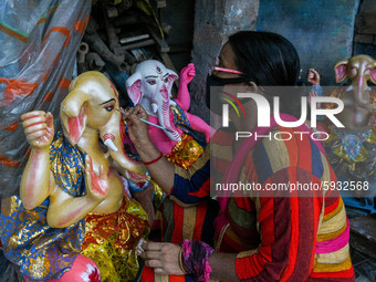 A lady artisan giving final touches to an idol of Ganesha.Ganesh chaturthi or Ganesh puja is the Hindu festival of celebrating the arrival o...