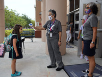 A school employee checks the temperature of a student as she returns to school on the first day of in-person classes in Orange County at Bal...