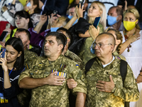 Veterans of the war in eastern Ukraine sing the anthem during the ceremony of rising the giant state flag of Ukraine the night before the Na...