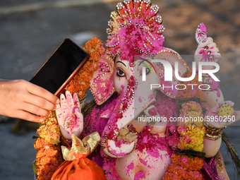 A devotee whispers a wish over phone in the ear of an idol of Hindu deity Ganesha, as part of a ritual on the occasion of Ganesha Chaturthi,...