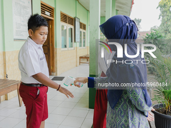 A teacher check body temperature of a student at Candirejo Elementary School, Semarang Regency, Central Java, Indonesia, on September 1, 202...