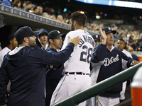 Detroit Tigers' J. D. Martinez gets a dugout congratulation after scoring a run on a triple hit by Nick Castellanos in the eighth inning of...