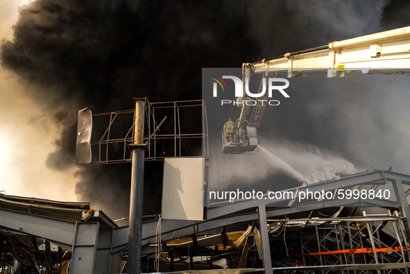 Firefighters throwing water in the epicenter of the fire in the seaport warehouse Above the city spread a dense black smoke that covered the...