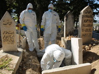 Volunteers from the Syrian Civil Defense, also known as the White Helmets, wear protective clothing and bury a death from the Coronavirus in...