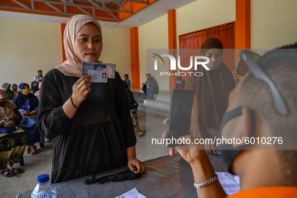A sfficer take a picture of a citizen who has received cash social assistance (BST) at the Palu Post Office, Central Sulawesi Province, Indo...