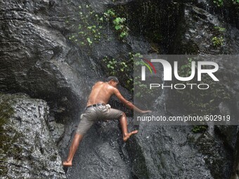 An Naga youth climb on the rock to dive into the water to cool off beside a small stream on a hot summer day in the outskirt of Dimapur, Ind...