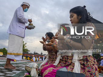 A Hindu religious leader sprinkles holy water on worshipers during the Kuningan Day prayer ritual at Pura Agung Wana Kerta Jagatnatha, Palu,...