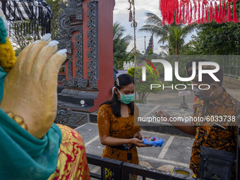 Hindus splash water on Canang Sari before participating in the Kuningan Day prayer ritual at Pura Agung Wana Kerta Jagatnatha, Palu, Central...