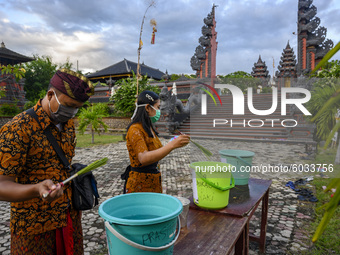 Hindus sprinkle holy water on their bodies before participating in the Kuningan Day prayer ritual at Pura Agung Wana Kerta Jagatnatha, Palu,...