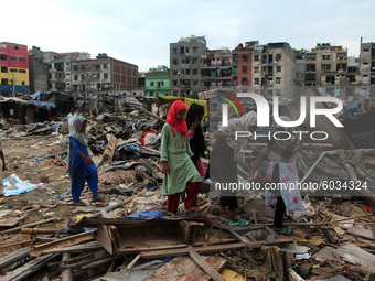 Residents are seen outside demolished slum dwellings after demolition drive by the Delhi Development Authority (DDA) against encroachments a...