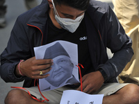 Nepalese youth as they arrive along with a printed portrait mask of Prime Minister KP Sharma Oli during a demonstration expressing Solidarit...