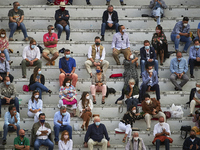People are seen sitting in the stands, wearing face masks and keeping the social distance established by government authorities, during the...