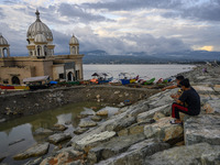 Residents enjoy the view near the floating mosque which collapsed into the sea after being hit by the tsunami on the beach of Kampung Lere,...