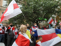 People hold historical white-red-white flags of Belarus during a rally of solidarity with Belarusian protests near the Belarusian Embassy in...