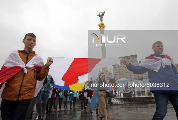 People carry a large historical white-red-white flag of Belarus during a rally of solidarity with Belarusian protests on Independence Square...