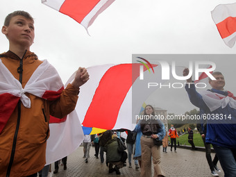 People hold a large historical white-red-white flag of Belarus during a rally of solidarity with Belarusian protests on Independence Square...