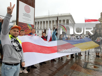 People hold a large historical white-red-white flag of Belarus during a rally of solidarity with Belarusian protests on the Independence Squ...