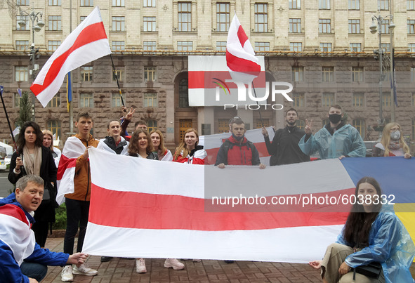 People hold flags in front of the Kyiv City Hall building with a huge former white-red-white flag of Belarus hanging on it, during a rally o...
