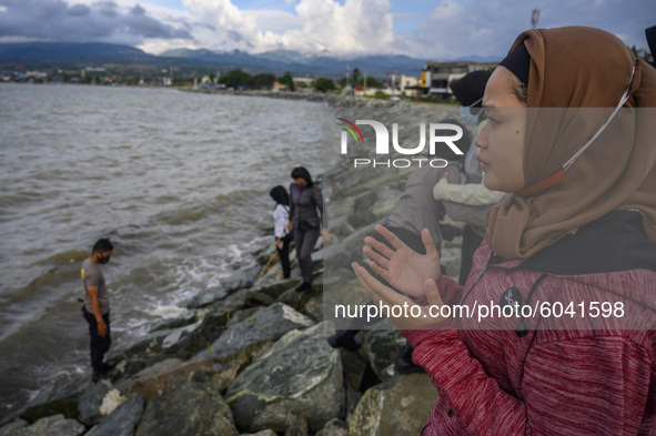 Families of disaster victims pray before sowing flowers at the former tsunami site on Talise Beach, Palu, Central Sulawesi Province, Indones...