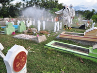 Health Officers from the local City Service, spray disinfectant liquid to prevent the spread of COVID-19, in the mass burial area of ​​victi...