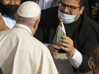 Faithful wearing face masks to prevent the spread of COVID-19 reach out to Pope Francis as he arrives for his weekly general audience in the...