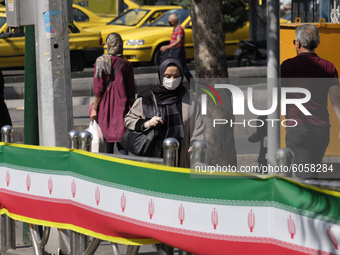 An Iranian woman wearing a protective face mask walks along an avenue in northern Tehran while the new coronavirus (COVID-19) disease rapid...