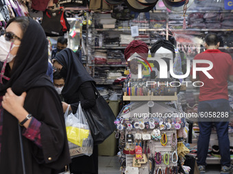 Iranians wearing face masks purchase as two mannequins are covered with face masks in a shop in northern Tehran while the new coronavirus (C...
